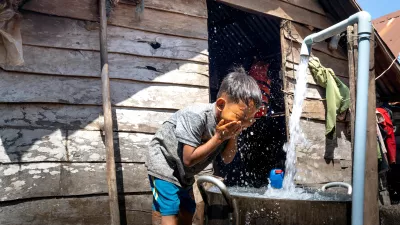 child washes his face at an outdoor sink