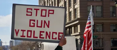 man holds a sign at a protest reading 'Stop gun violence'