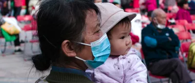 woman wearing a mask holds her grandchild
