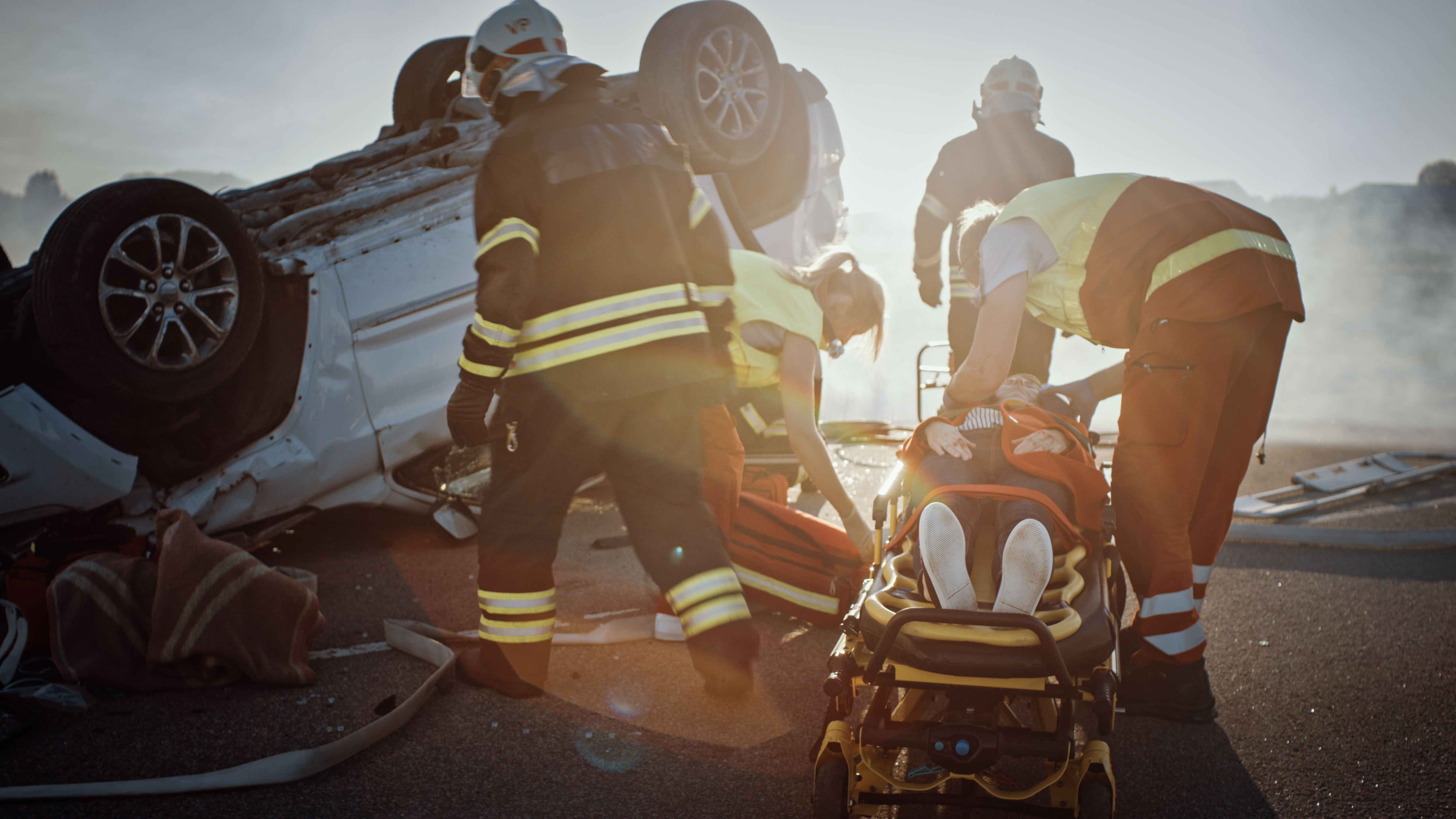 Emergency workers attend to someone at the scene of a car accident