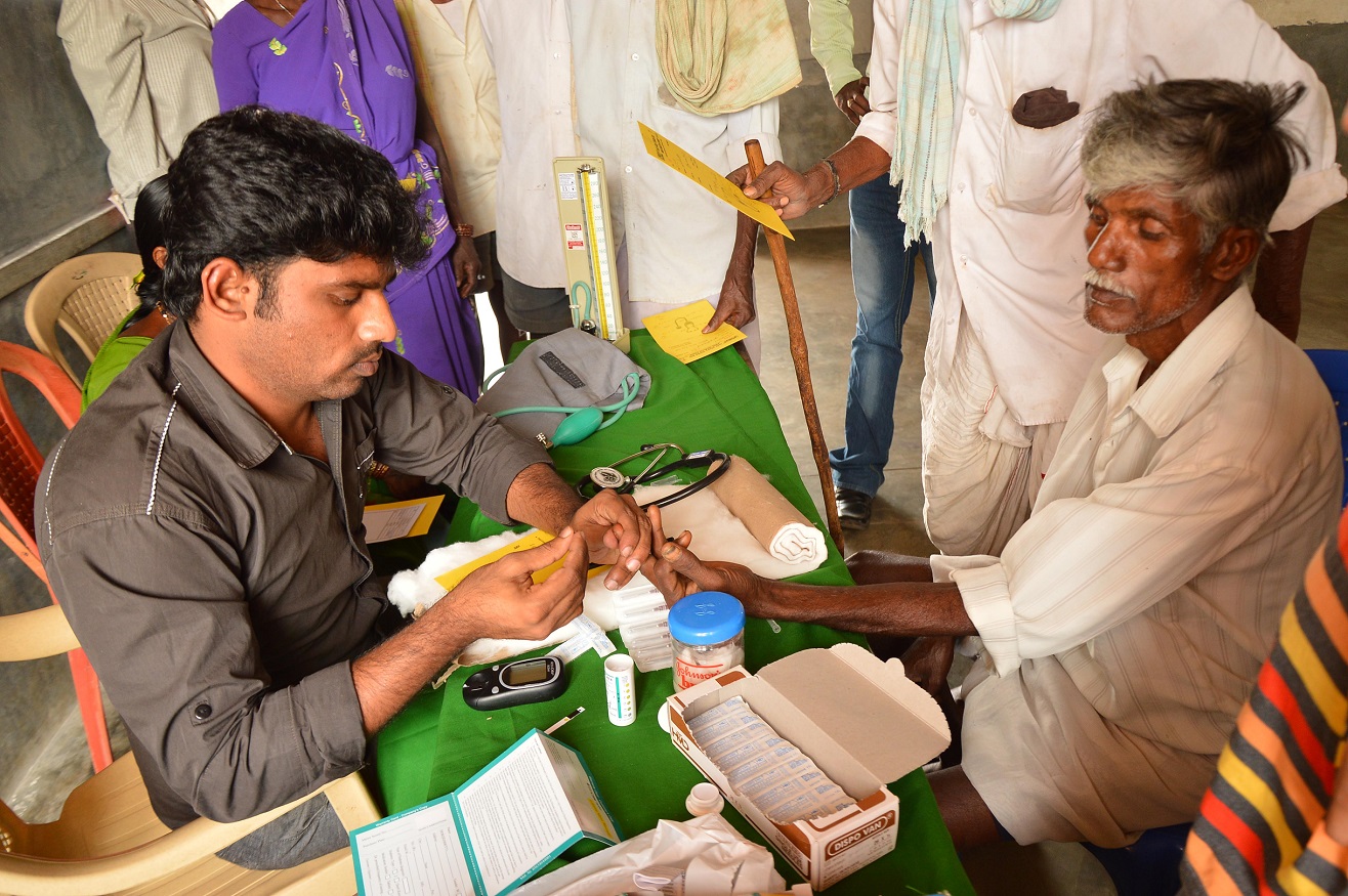 doctor in India takes a patient's blood sample with a finger prick