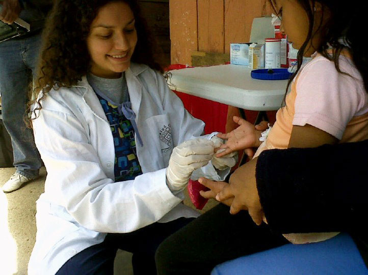 a doctor administers a finger prick blood test to a young girl