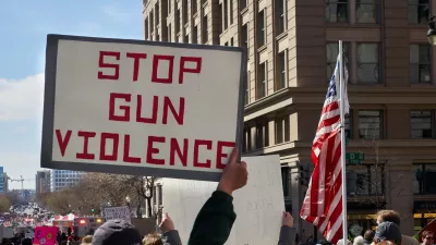 man holds a sign at a protest reading 'Stop gun violence'