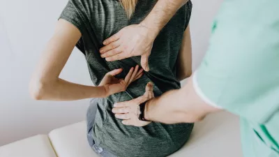 a doctor examines a woman with low back pain