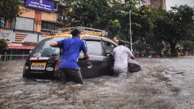 two men push a car through a flooded street