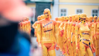 an art installation depicting bodies wrapped in yellow tape with slogans protesting against domestic violence