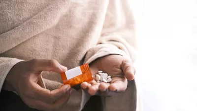 hands holding a prescription bottle with pills spilling out