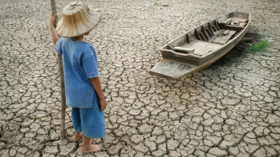 A child looks out across a dried up lake.