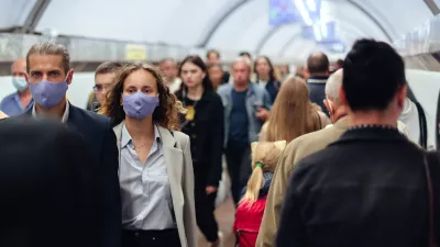 couple wearing face masks moves through crowd in subway terminal