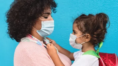 mother and daughter wearing face masks, looking at each other