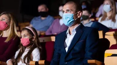 people watching a performance in a theater wearing masks