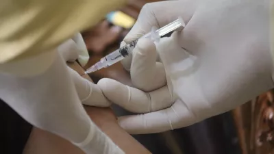 gloved hands administering a vaccine into a person's shoulder