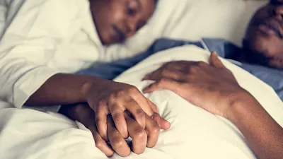 Black couple holding hands in bed