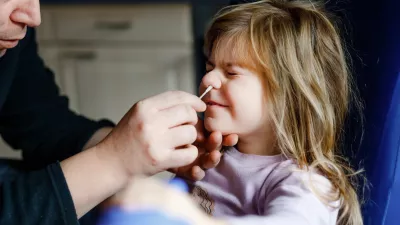 father administering nasal covid test to young daughter