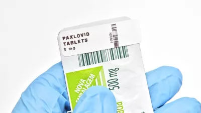 gloved hand holding a packet of Paxlovid pills