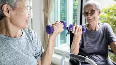 two elderly women smile while lifting weights
