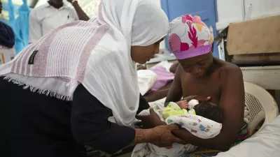 Hospital nurse assists a woman with her newborn
