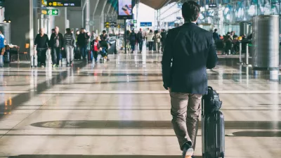 man walks through the airport with a suitcase