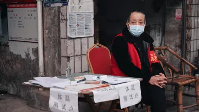 man wearing a mask sits at a temperature check station on the street in China