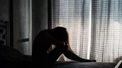Lonely young woman depressed and stressed sitting in the dark bedroom