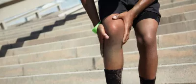 person clutching their knee in pain