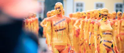 an art installation depicting bodies wrapped in yellow tape with slogans protesting against domestic violence