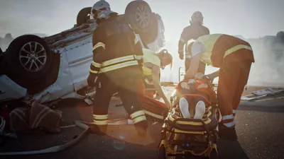 emergency workers attend to a crashed car